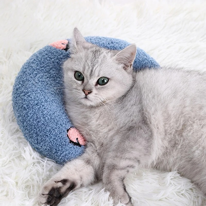 Coussin pour chat avec un chat allongé dessus, offrant soutien ergonomique et confort grâce à sa forme demi-lune et fausse fourrure douce.