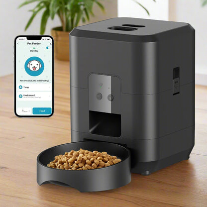 Distributeur croquettes chat Smartphone à côté d'un distributeur intelligent noir avec bol de croquettes, illustrant la gestion à distance avec application mobile de l'alimentation féline.