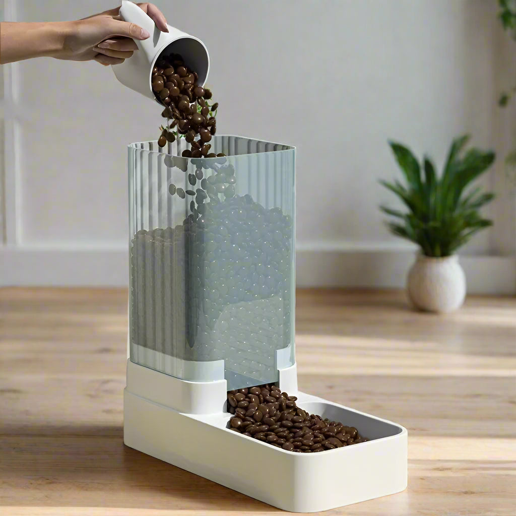 distributeur croquette chat à gravité avec main versant des croquettes dans le récipient